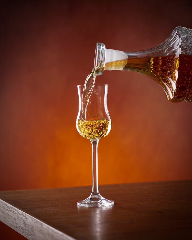 将酒精从水晶醒酒器倒入格拉帕酒杯