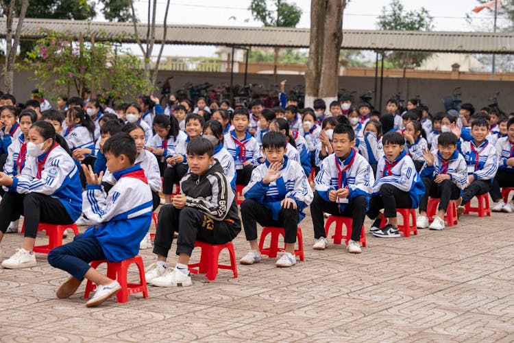 小学生坐在外面的椅子上