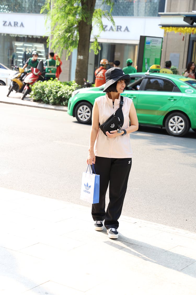 城市人行道上戴着帽子和袋子的女人