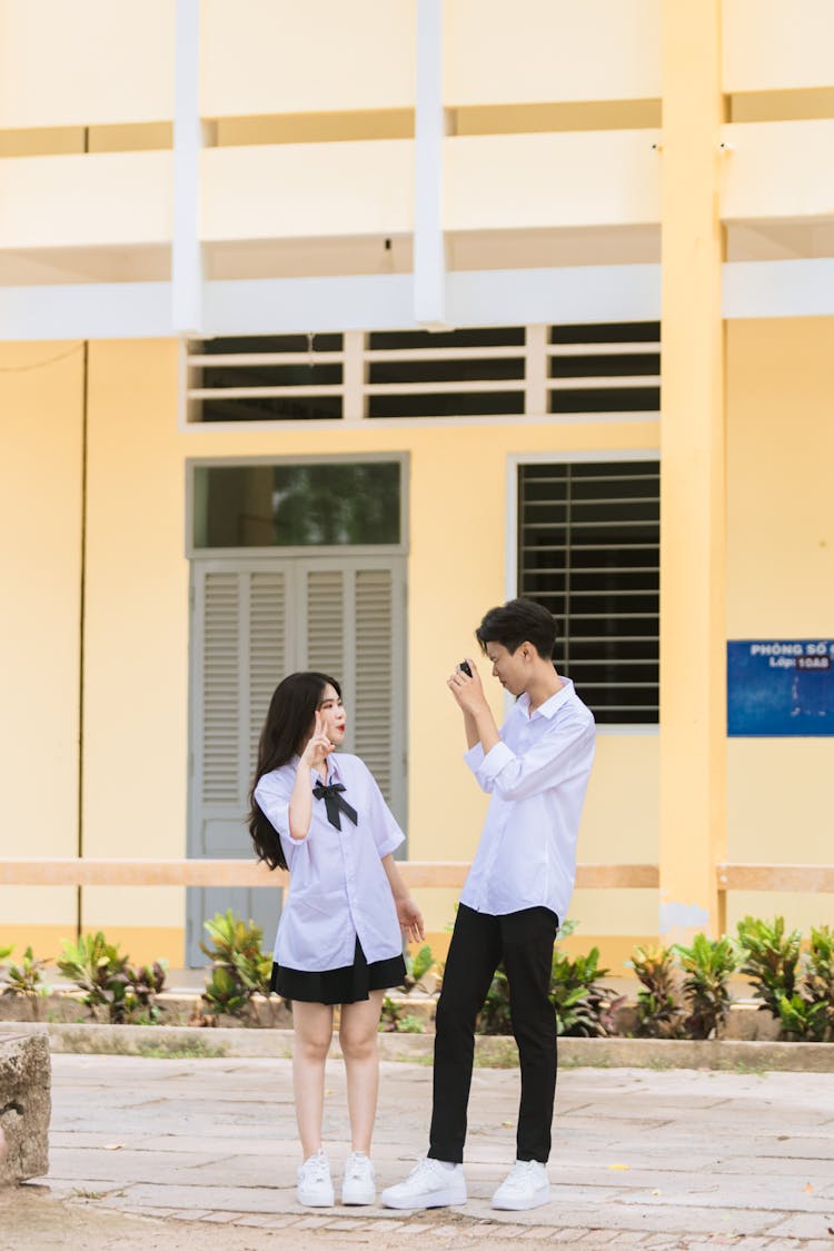 一个男孩在建筑物外给一个女孩拍照