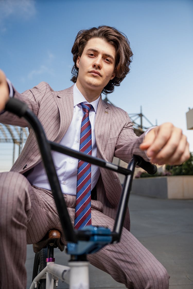 穿着西装的年轻优雅男子坐在BMX自行车上