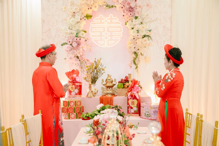 婚礼上，一对穿着传统服装的男女站在桌子旁，手里拿着鲜花