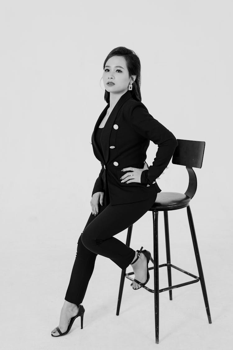 一个穿着西装的女人在凳子上摆姿势的黑白照片