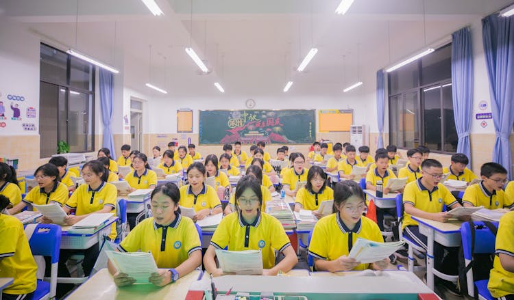 穿着黄色Polo衫的青少年在教室的课桌前学习