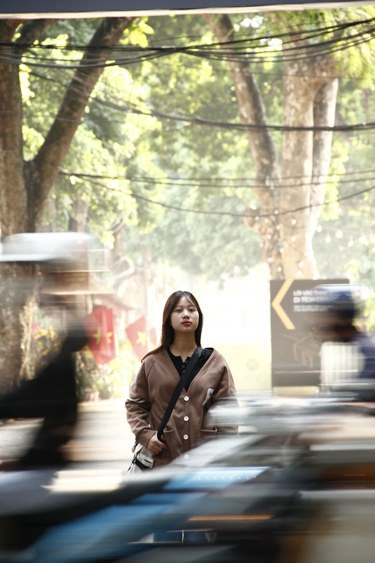 一个女人站在街道上，周围是行驶的车辆