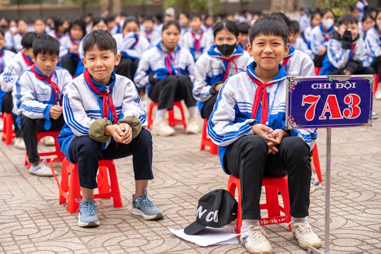 小学生坐在外面的椅子上