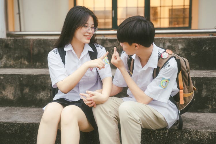 穿着校服的青少年夫妇坐在台阶上