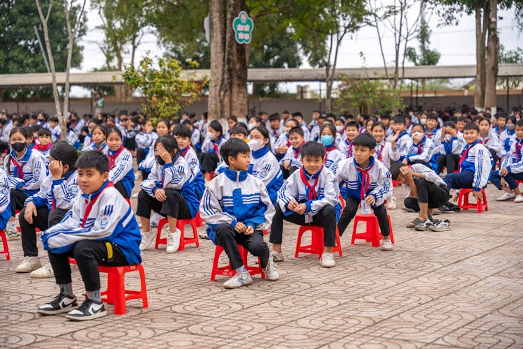 小学生坐在外面的椅子上