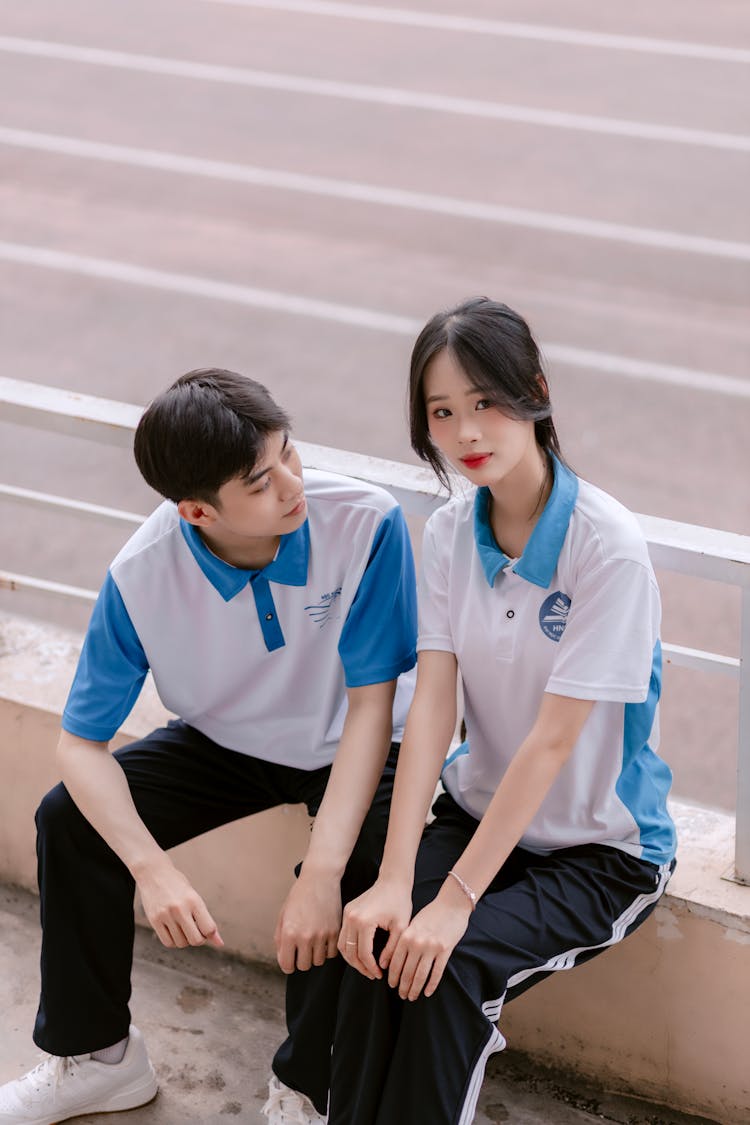 墙上坐着一对穿着运动服的年轻男女