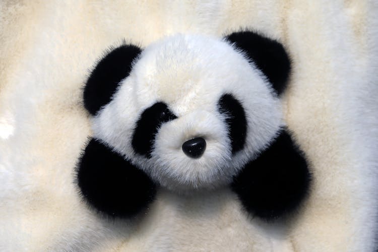 毛皮背景上的可爱熊猫毛绒玩具