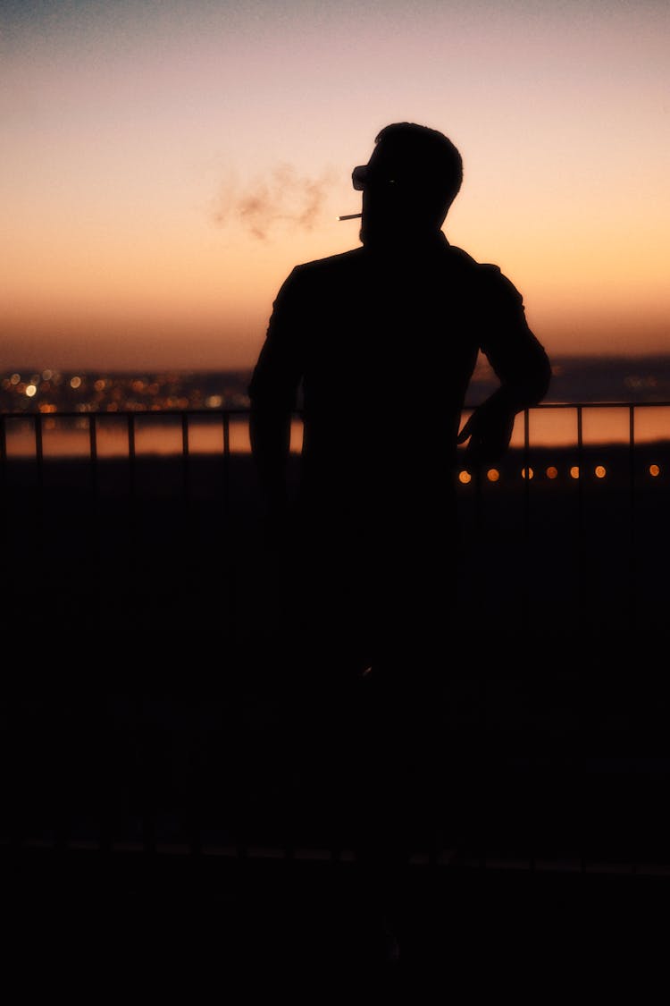 一个男人在日落时抽烟的剪影